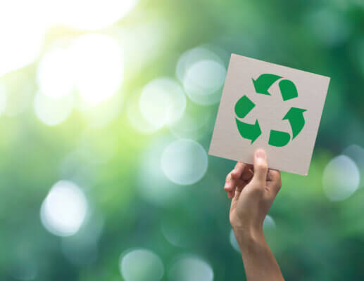  Hand holding recycle symbol on green background.