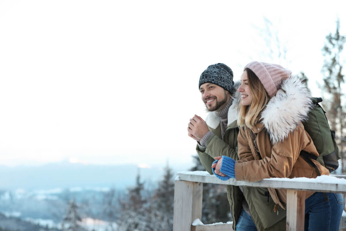 Couple with backpacks enjoying mountain view during winter vacation.