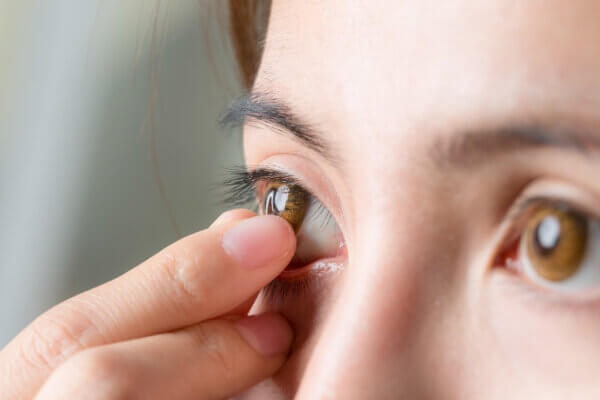 Close-up shot of young woman wearing or remove contact lens.