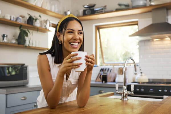 Woman drinking hot drink in home kitchen.