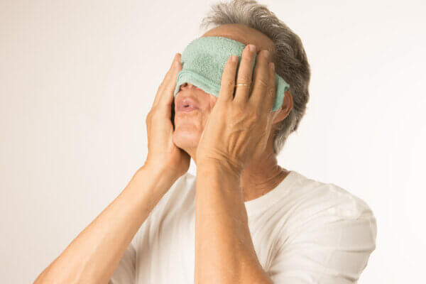 Man with a warm compress over his eyes. 