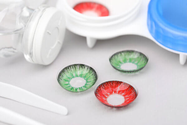 Different color contact lenses and tweezers on white background, closeup