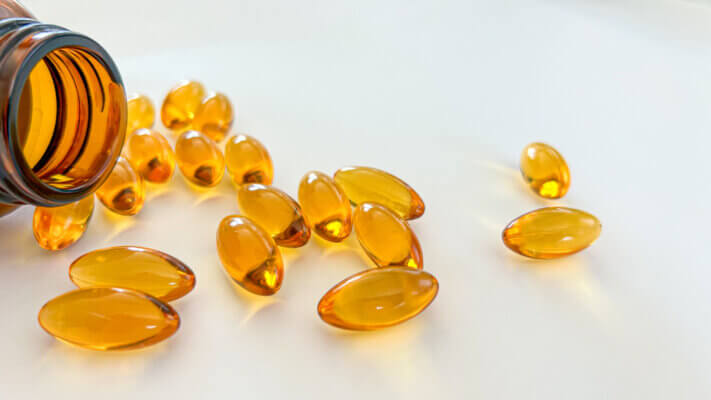 Omega-3 capsules spilling from brown bottle. 