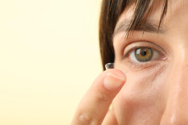 Woman inserting contact lens into eye 