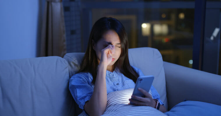 A woman sitting on a couch holding a cell phone. 